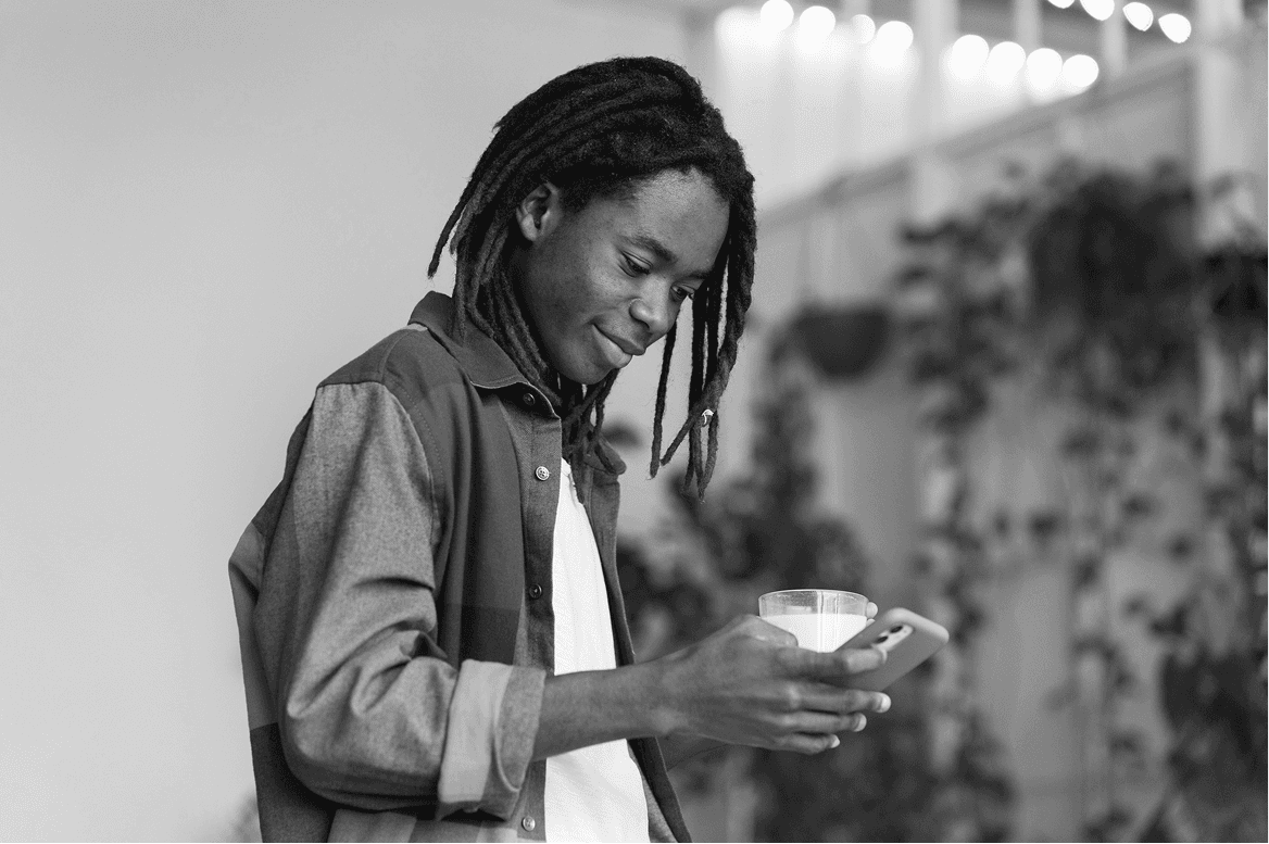 Man with dreads smiling while using smartphone