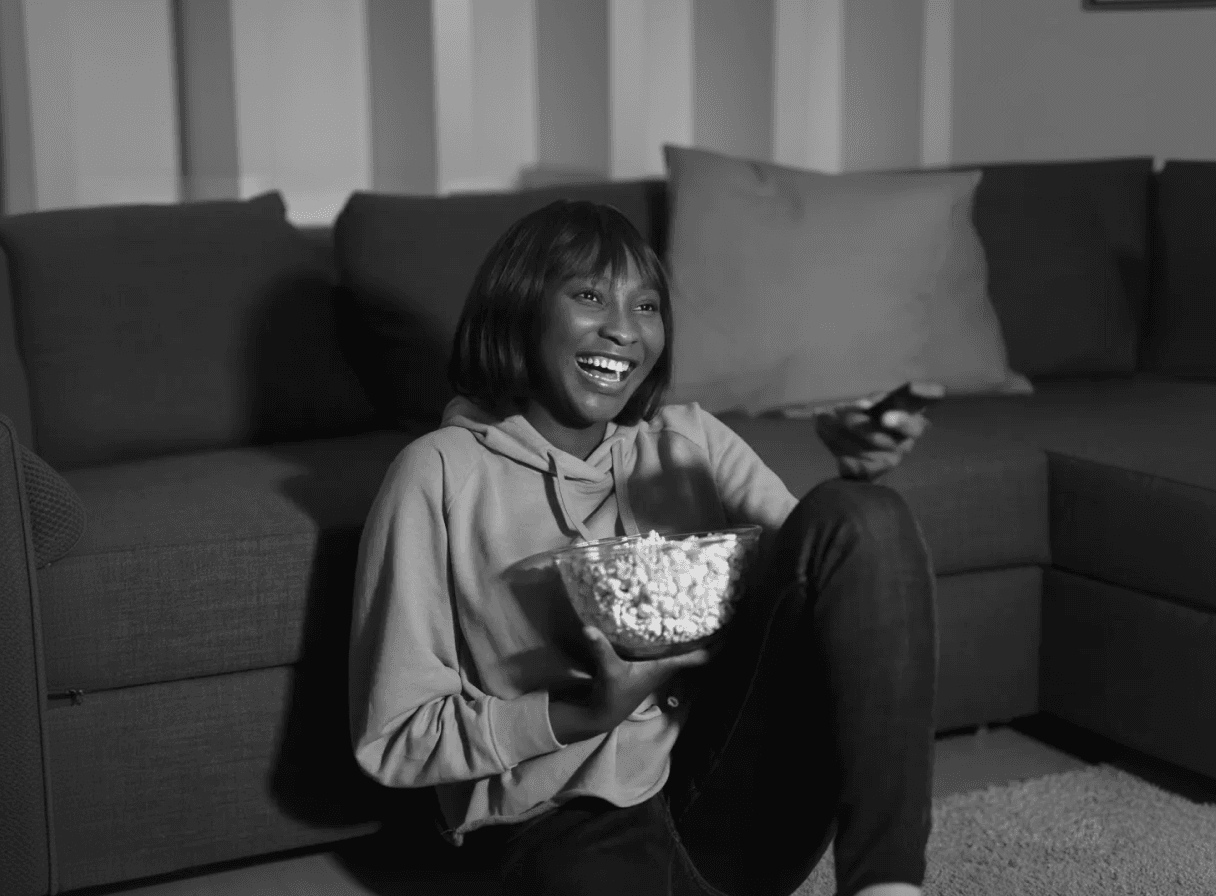 Happy woman watching TV with remote control